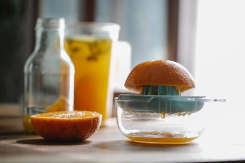 Half of delicious sweet orange placed on plastic orange juicer placed on kitchen table