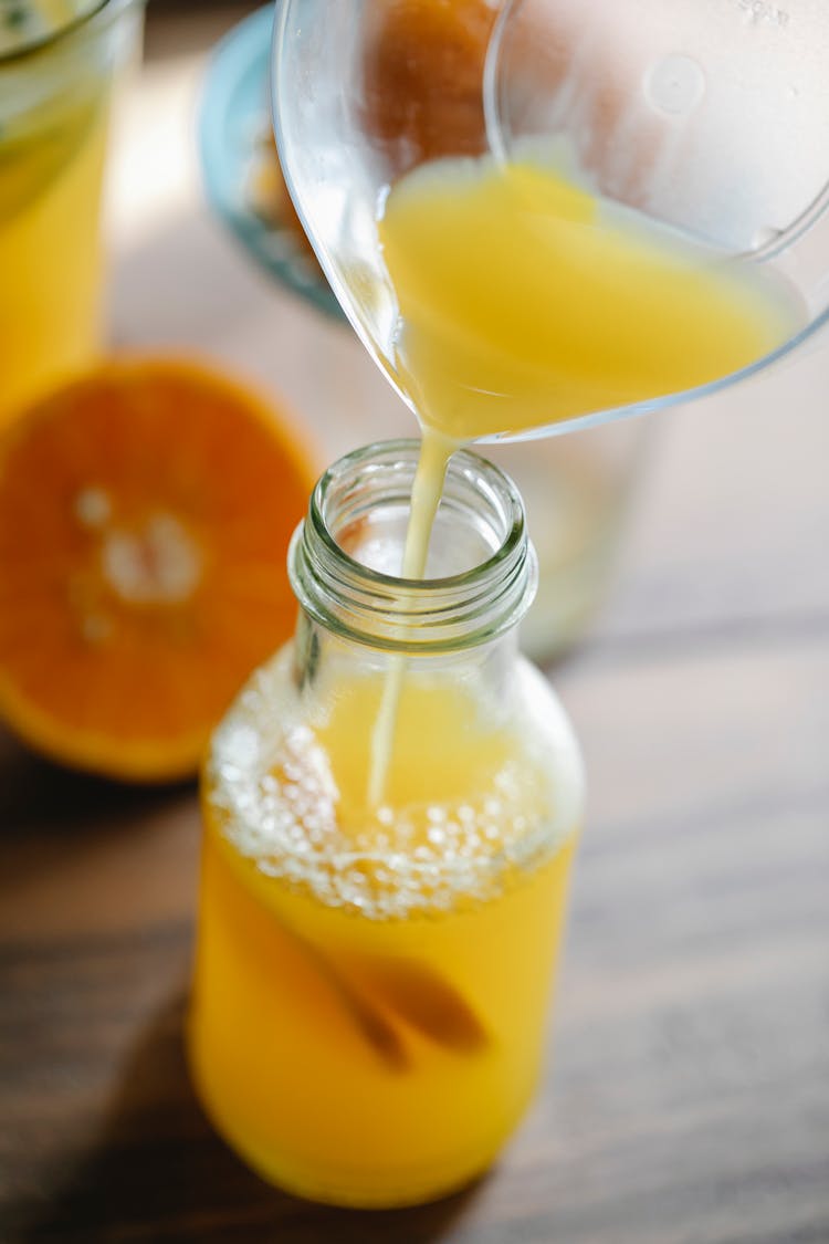 Fresh Orange Juice Pouring Into Glass Bottle