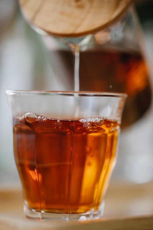 Free Aromatic freshly brewed black tea pouring from teapot into glass placed on tray Stock Photo