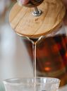 Crop person pouring fresh tea from French press into cup