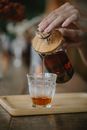 Crop faceless woman pouring fresh tea into glass