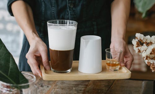 Crop faceless woman serving cold coffee with cognac