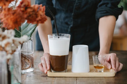 Crop unrecognizable woman serving iced coffee with shot of cognac