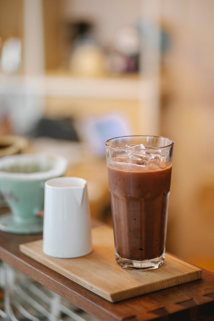 Delicious Iced Coffee On Wooden Board With Milk Jigger