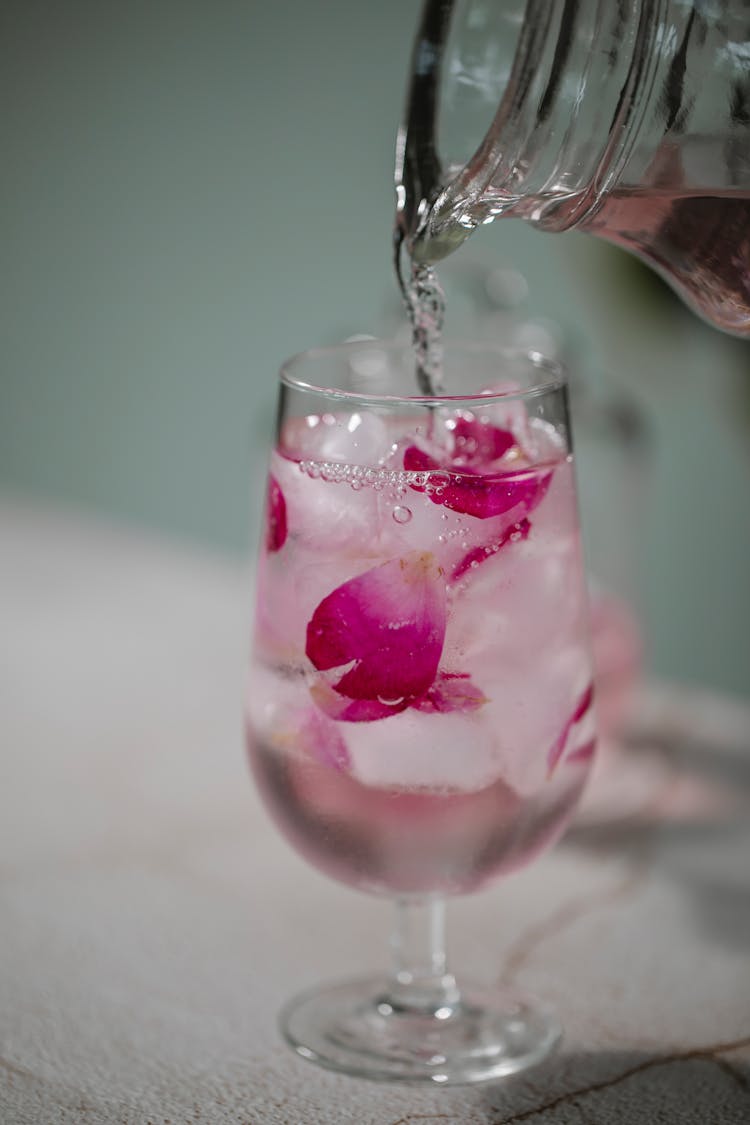 Cold Water Pouring Into Glass With Rose Petals