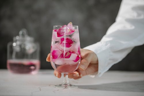 Personne Tenant Un Verre à Vin Clair Avec Un Liquide Rose