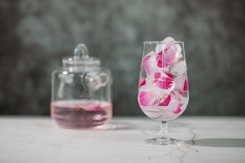 Glass with ice cubes and rose petals