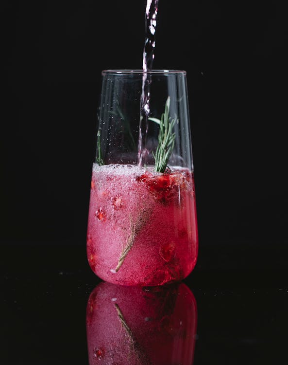 Free Crystal clean glass of red cocktail with berries and rosemary on black background Stock Photo