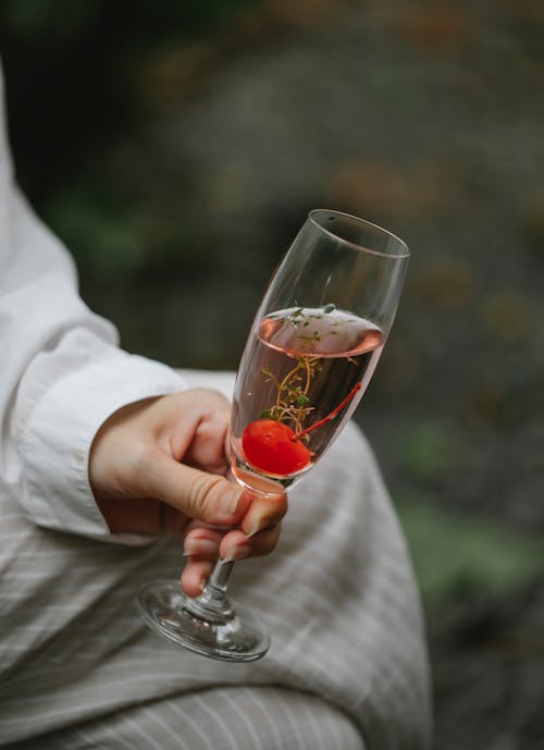 Anonymous woman drinking cocktail with cherry