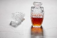 From above of open crystal glass jug with alcoholic beverage placed on white table with cracks