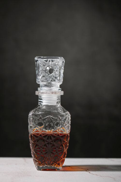 Free Crystal transparent decanter with whiskey placed on table in studio against black background Stock Photo