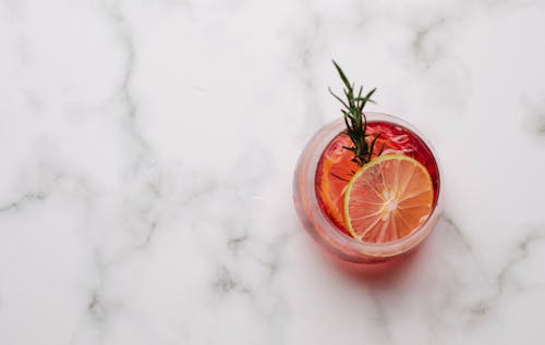 Glass with cocktail with lemon and rosemary placed on table