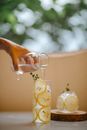 Crop person pouring water in lemonade