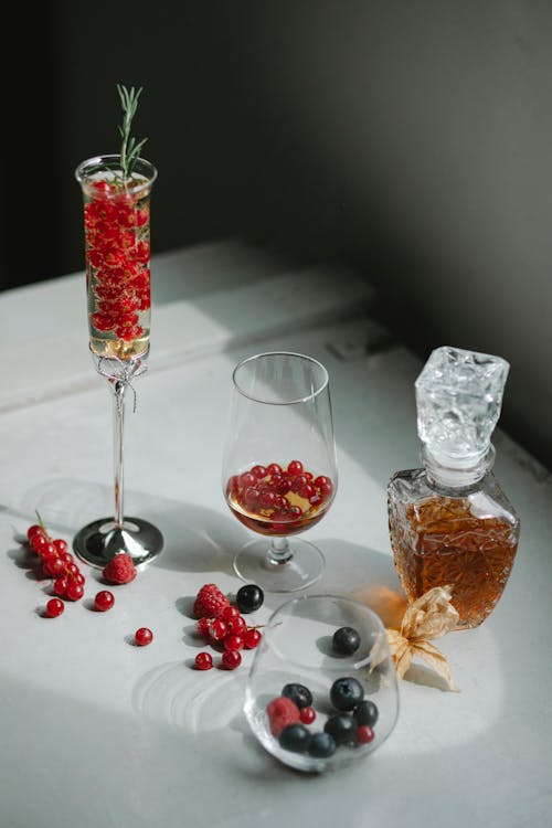 Free High angle of transparent glasses with ripe fresh berries and rosemary placed on table near crystal jug with alcoholic beverage Stock Photo