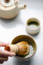 Crop woman whipping matcha tea