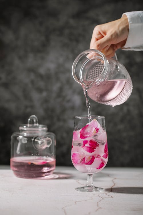 Free Crop person pouring rose water in glass Stock Photo