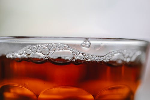 Closeup of alcoholic drink with small bubbles in clean transparent glass on white background