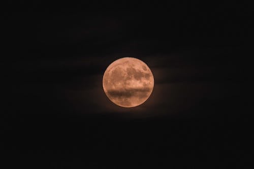 Moon natural satellite of Earth shining over dark sky with clouds at night