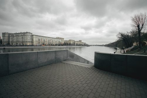 Free A moody urban riverside landscape under an overcast sky, showcasing architecture and nature. Stock Photo