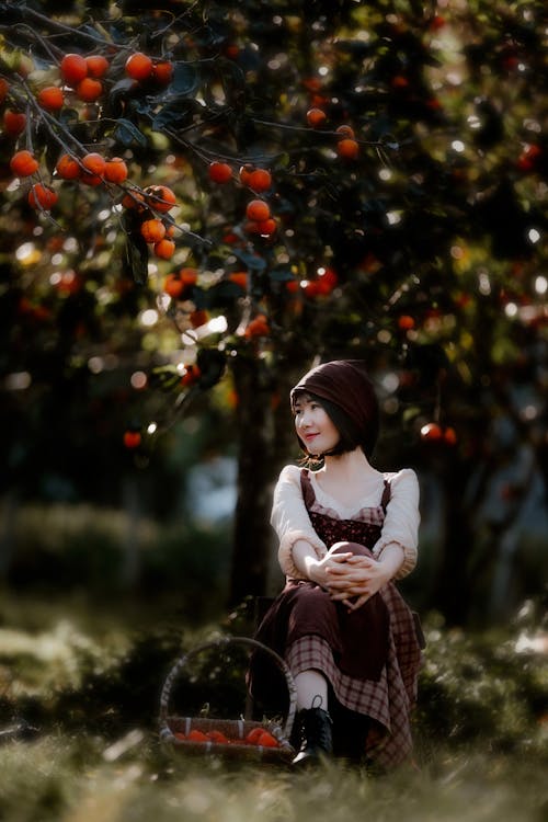 Peaceful Asian woman sitting under fruit tree