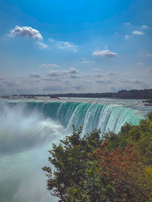 Free Stunning vertical shot of Niagara Falls cascading under a clear blue sky, perfect for travel and nature themes. Stock Photo