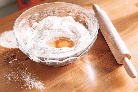 Mixing flour and eggs for baking on a wooden table.
