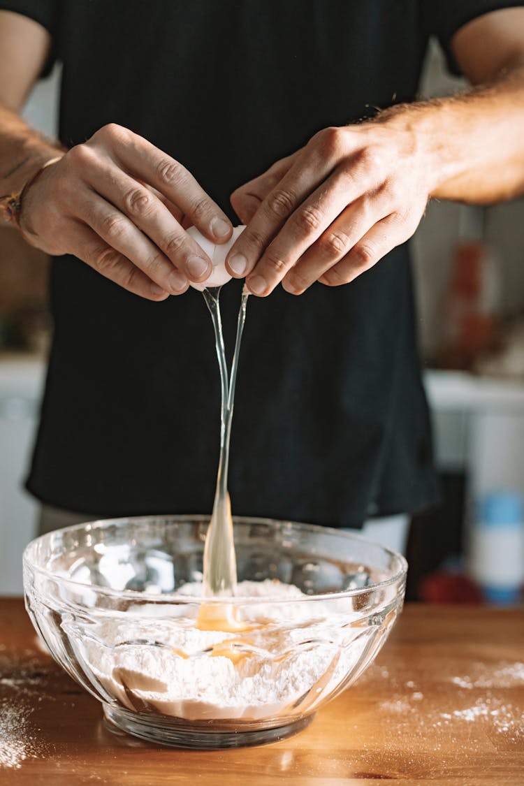 Man Adding Egg To Flour