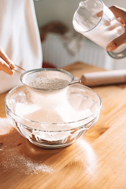 Free Close-up of flour sifting in a sunny kitchen, showing homemade baking preparation. Stock Photo