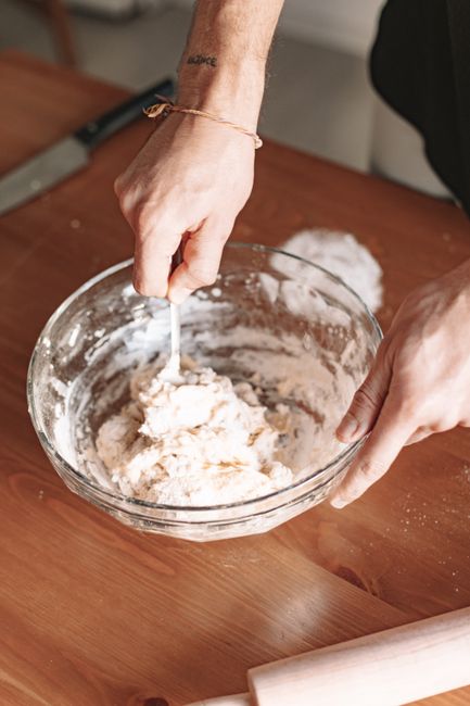 Fotomural Primer plano de manos mezclando masa en un tazón de vidrio, perfecto para fotografía de cocina y alimentos.