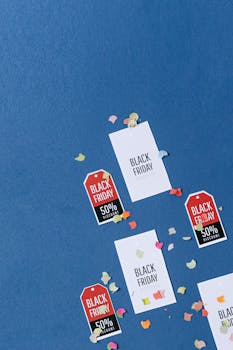 Colorful sale tags and confetti on a textured blue surface for Black Friday deals.