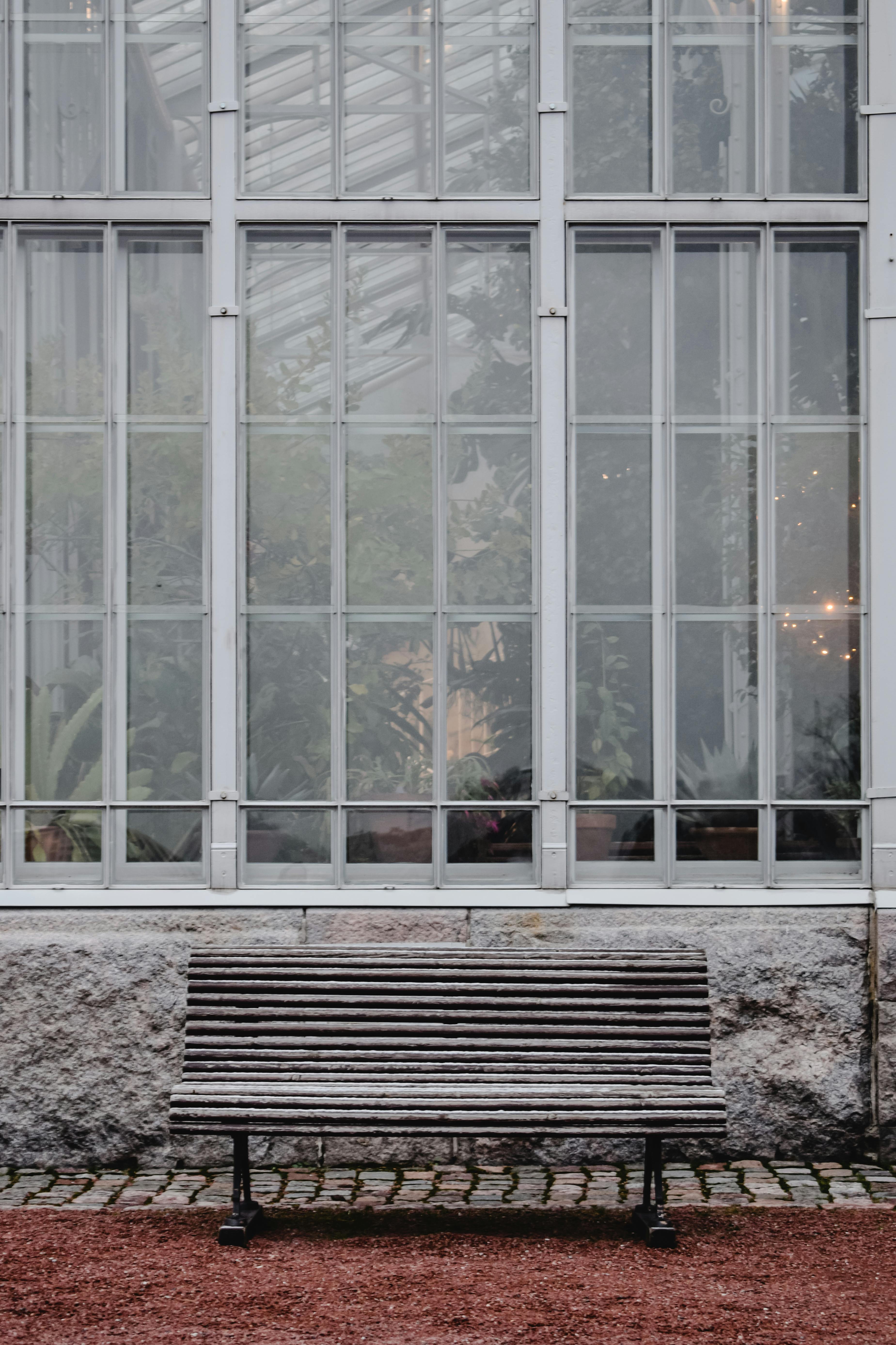 Wooden bench against a large glass building in Helsinki, Finland.