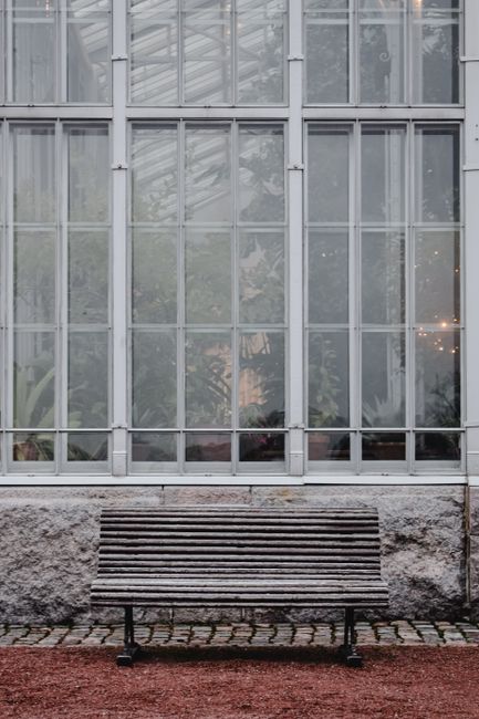 Wooden bench against a large glass building in Helsinki, Finland.