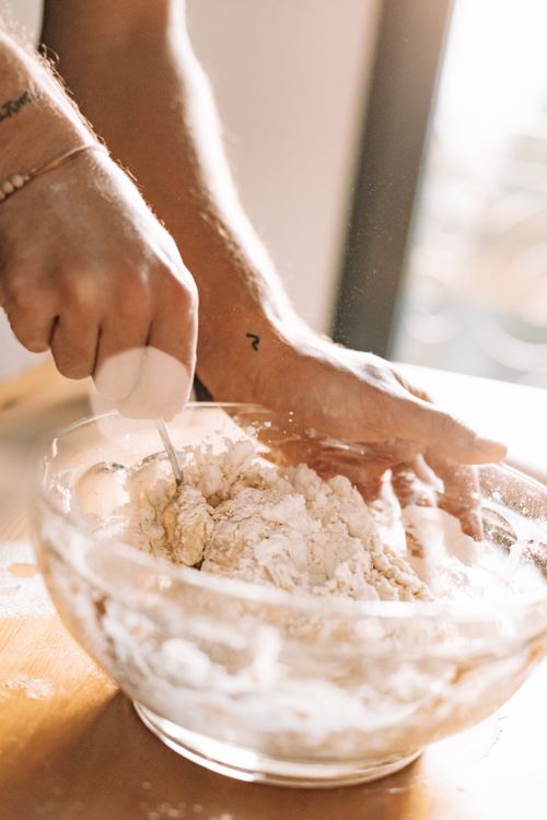 Free Close-up of hands mixing dough in a clear bowl during day in a cozy kitchen setting. Stock Photo