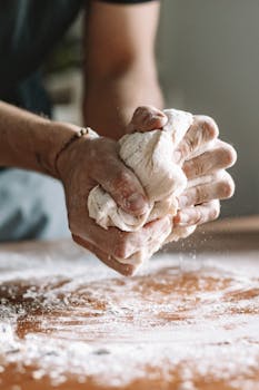 Close-up of hands kneading dough on a floured surface, showcasing traditional baking techniques.