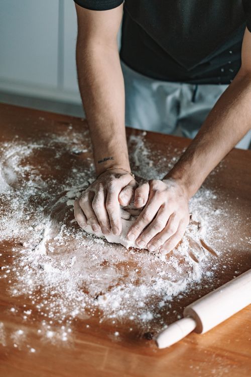 Free Close-up of hands kneading dough on a floured wooden table, capturing the essence of homemade baking. Stock Photo