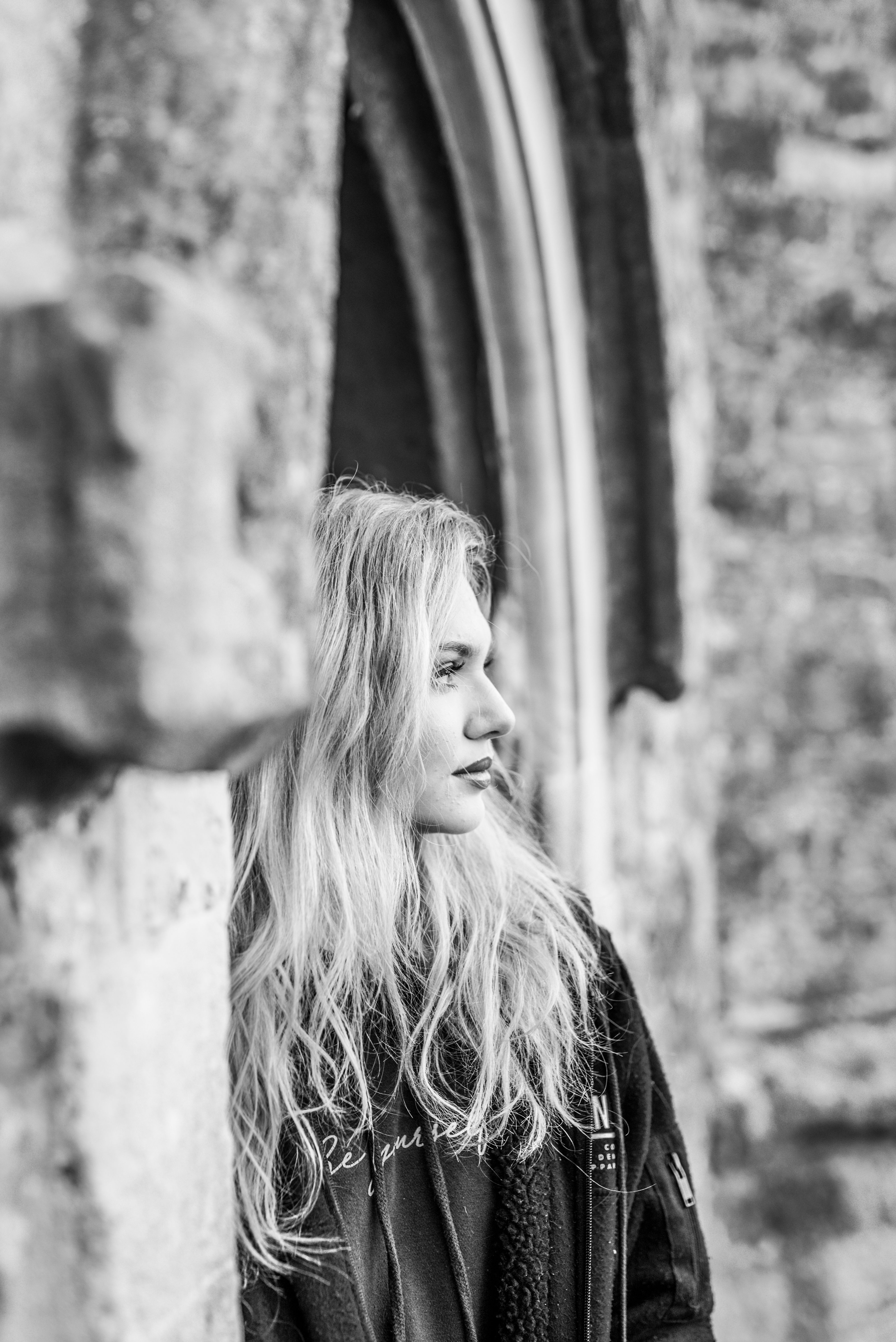 Artistic black and white side portrait of a woman standing outdoors.