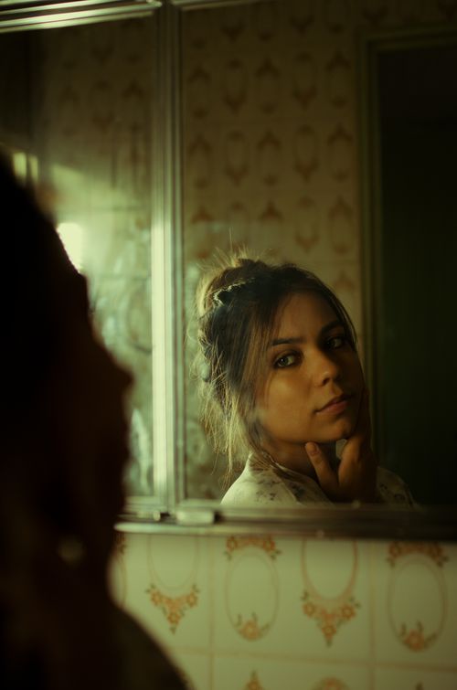 Free A woman reflects thoughtfully in a vintage bathroom mirror, capturing an introspective mood. Stock Photo