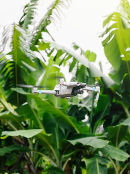 Drone in flight amidst vibrant tropical leaves on a clear day, showcasing outdoor exploration.
