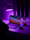 Laptop and a Smartphone on a Desk with a Purple Light Lamp