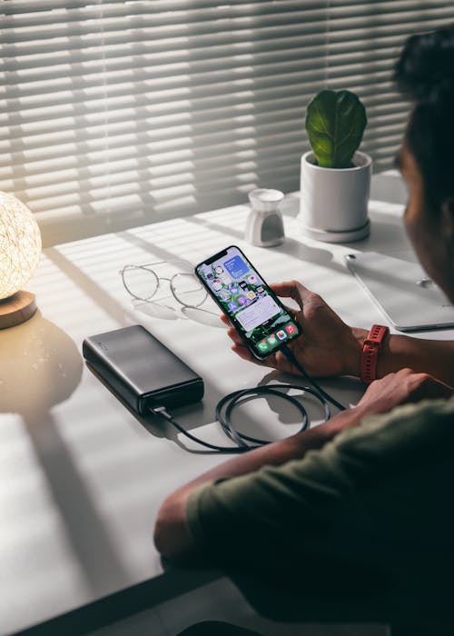 A Person Holding a Smartphone beside a Power Bank