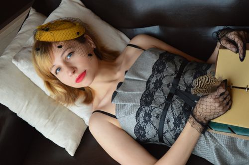 Free High angle of alluring female author in retro outfit with veil on hat and notepad looking at camera while lying on couch Stock Photo