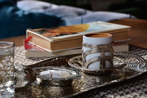 Free Close-up of a coffee cup on an ornate metal tray with books, creating a warm, cozy atmosphere. Stock Photo