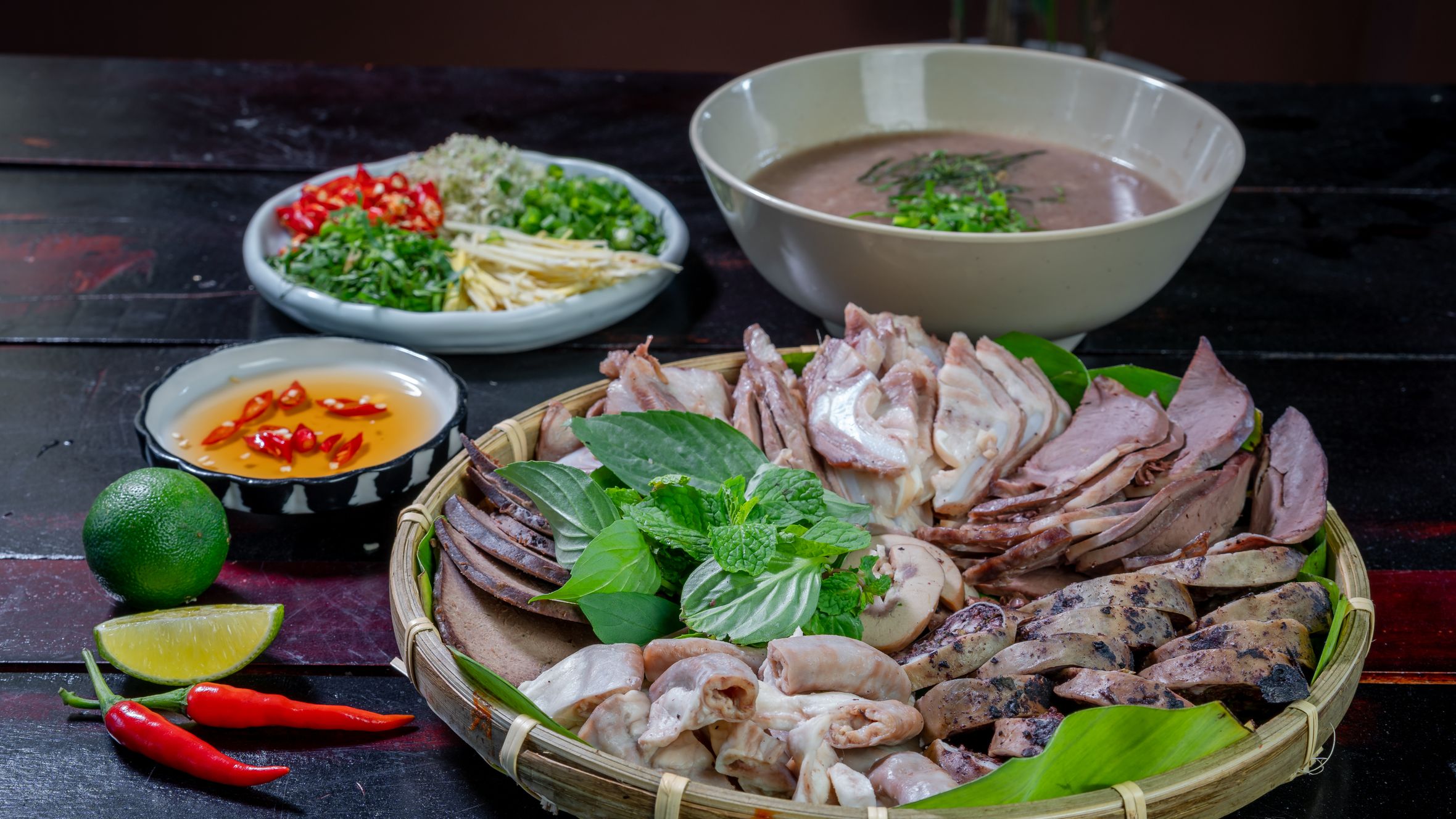 A vibrant display of traditional Vietnamese cuisine featuring meats, herbs, and dipping sauces.