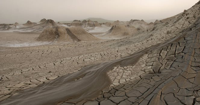 Explore the arid landscapes of Qobustan, Azerbaijan, featuring cracked mud formations and barren terrain.