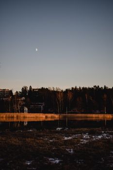 芬兰赫尔辛基的冬季场景宁静而半月形，树木和湖泊倒映着傍晚的天空