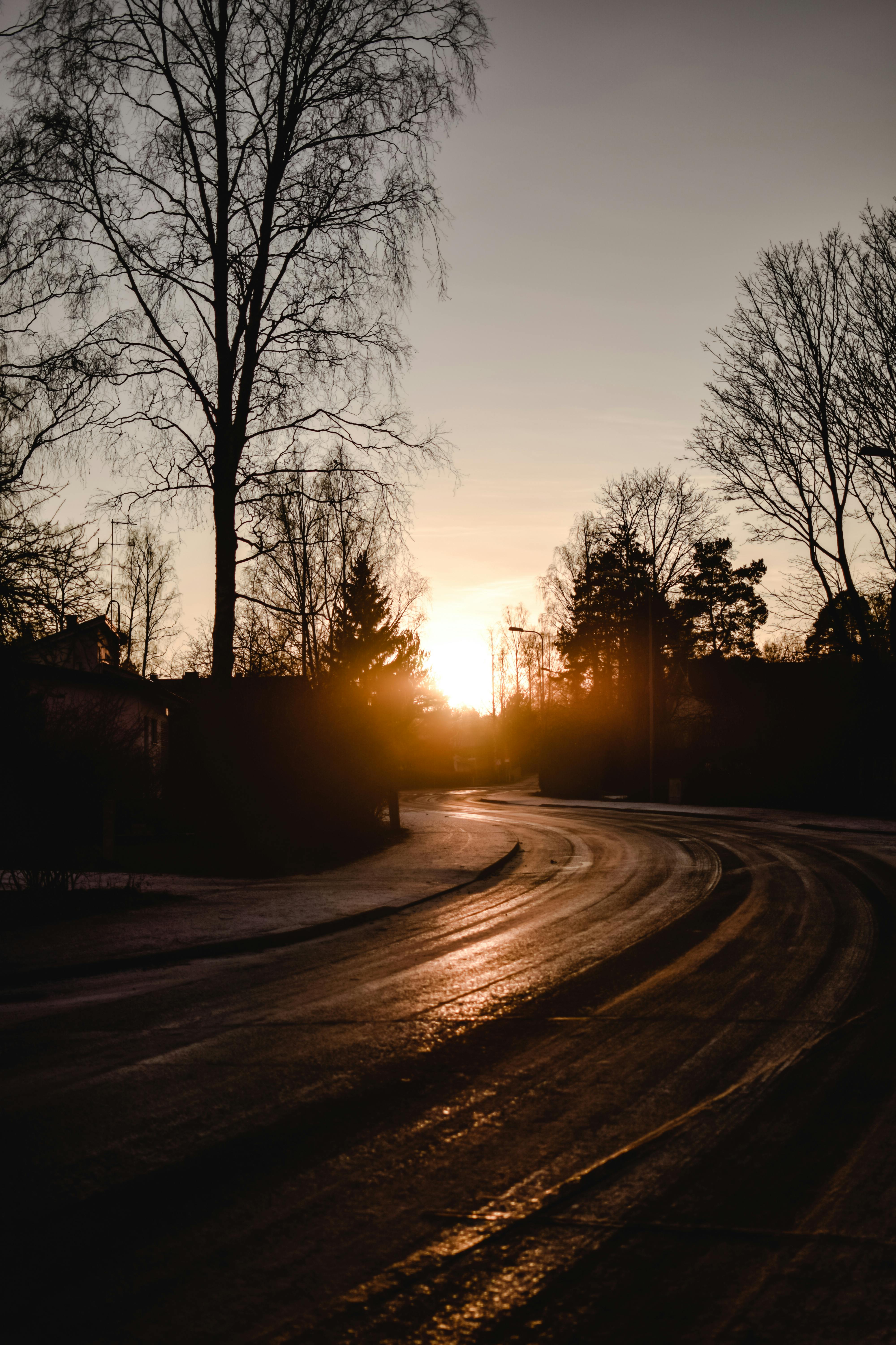 芬兰赫尔辛基冰冷的道路上，宁静的冬季日落洒下温暖的色调