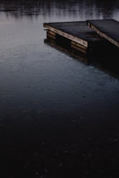 A tranquil view of a wooden dock over a still lake in Helsinki, Finland, creating a serene atmosphere.