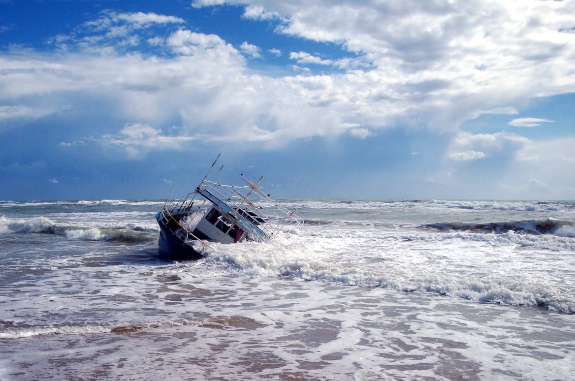 Free Waves Crashing on a Boat on Seashore Stock Photo