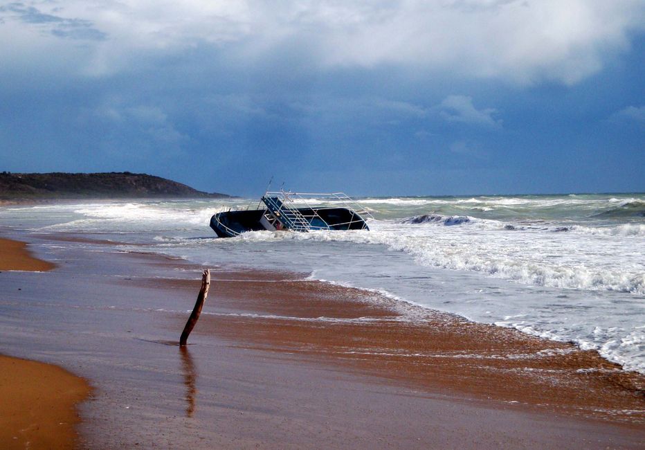 Dramatic view of a shipwreck on a stormy Sicilian beach, showcasing the power of nature.