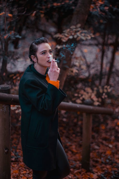 Woman Wearing a Black Coat Smoking a Cigarette